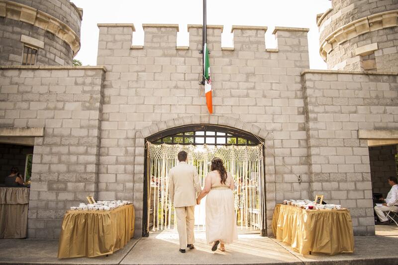 A bride and groom holding hands walking through a castle gate